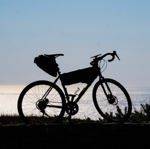 Vélo gravel équipé  d'une sacoche de selle et d'une sacoche de cadre pour voyager en mode bikepacking