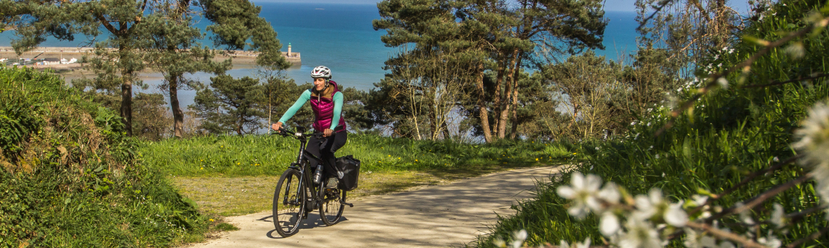 femme cycliste en bretagne avec un vélo électrique et des sacoches