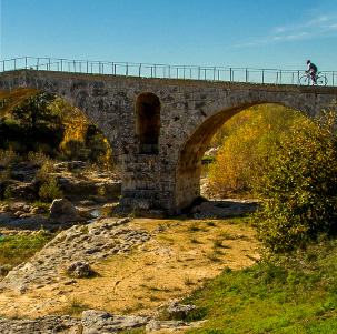 Cycliste franchissant un joli pont de pierre